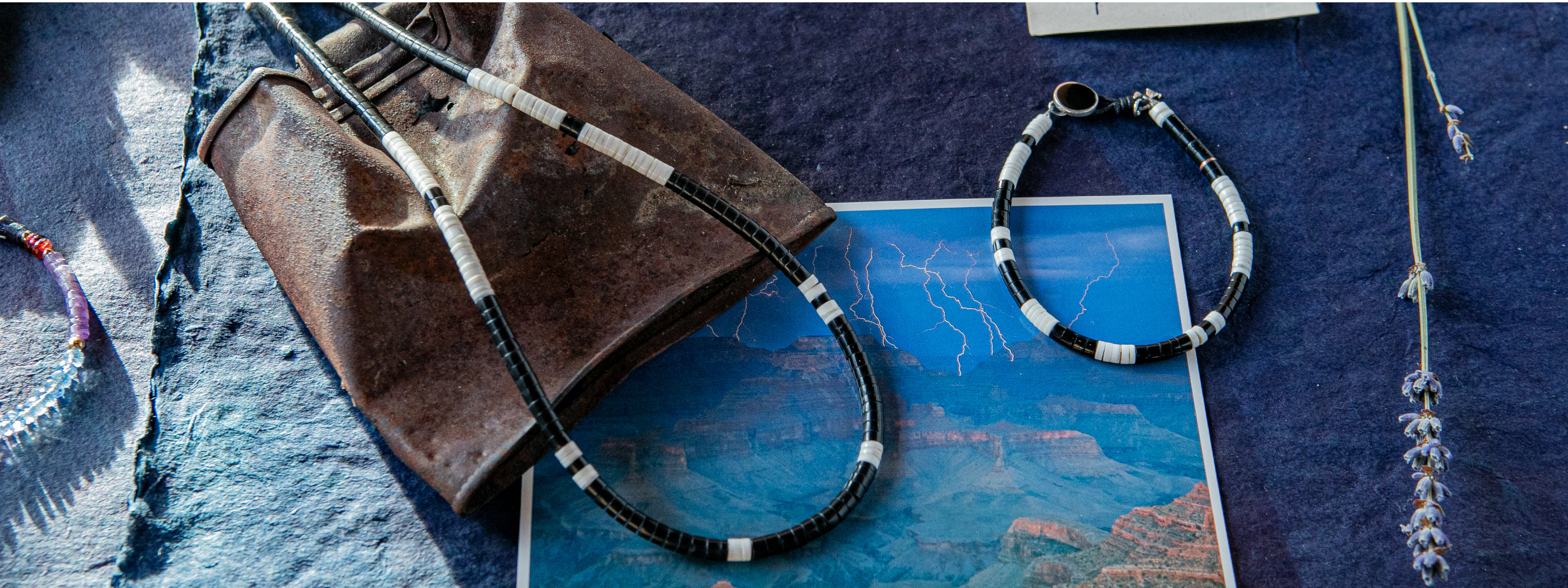 Various pieces of silver and turquoise jewelry in necklaces, bands, and rings sit on a cracked white surface.