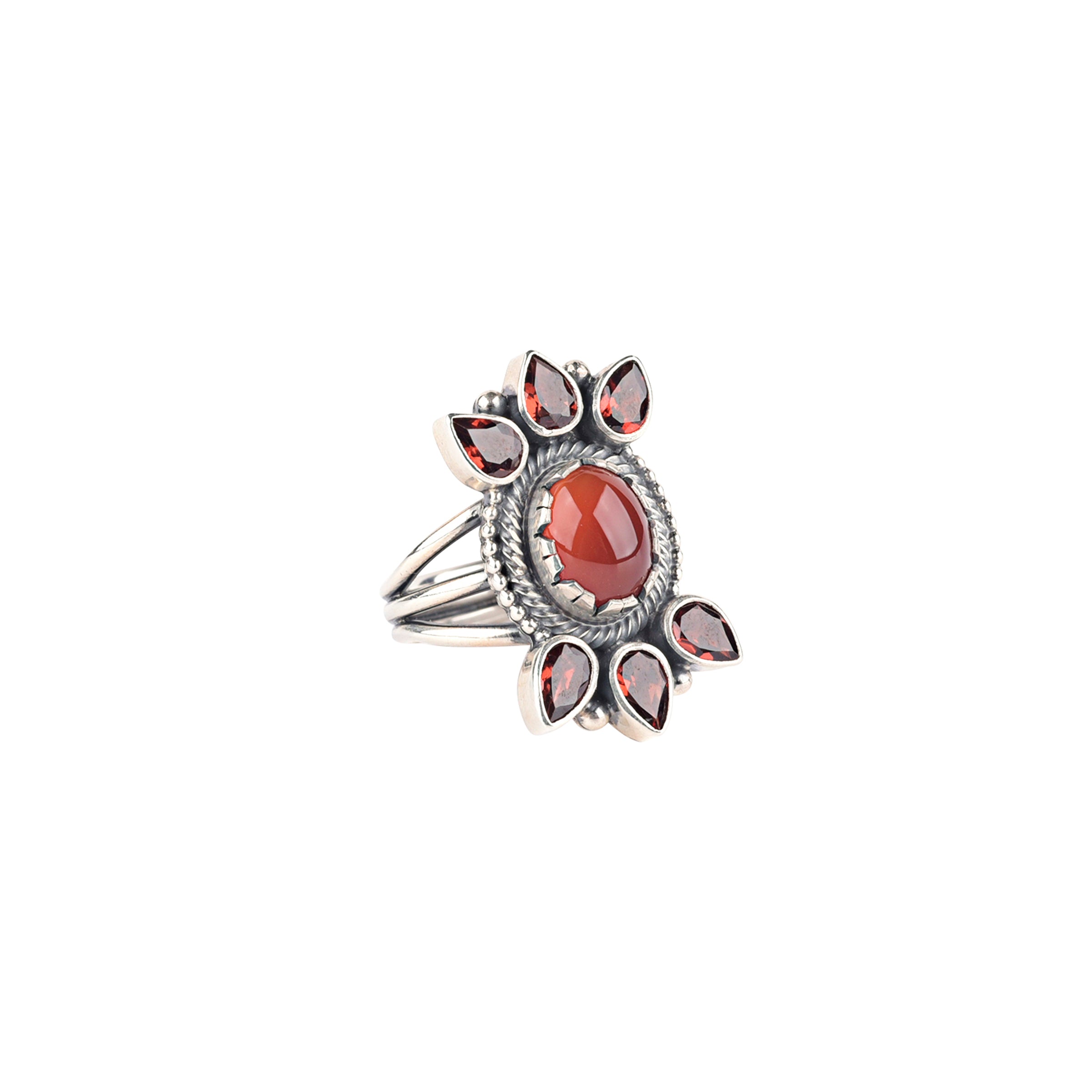 Sterling silver ring with center red stone surrounded by rope detailing and 3 teardrop shapes going outward on the top and bottom with 3 band shank.