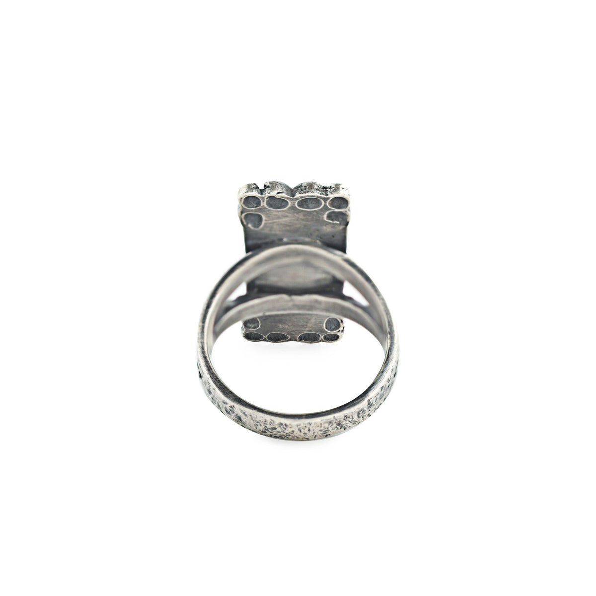 A rectangular sterling silver ring with red coral stones, featuring a textured design around the split shank band.