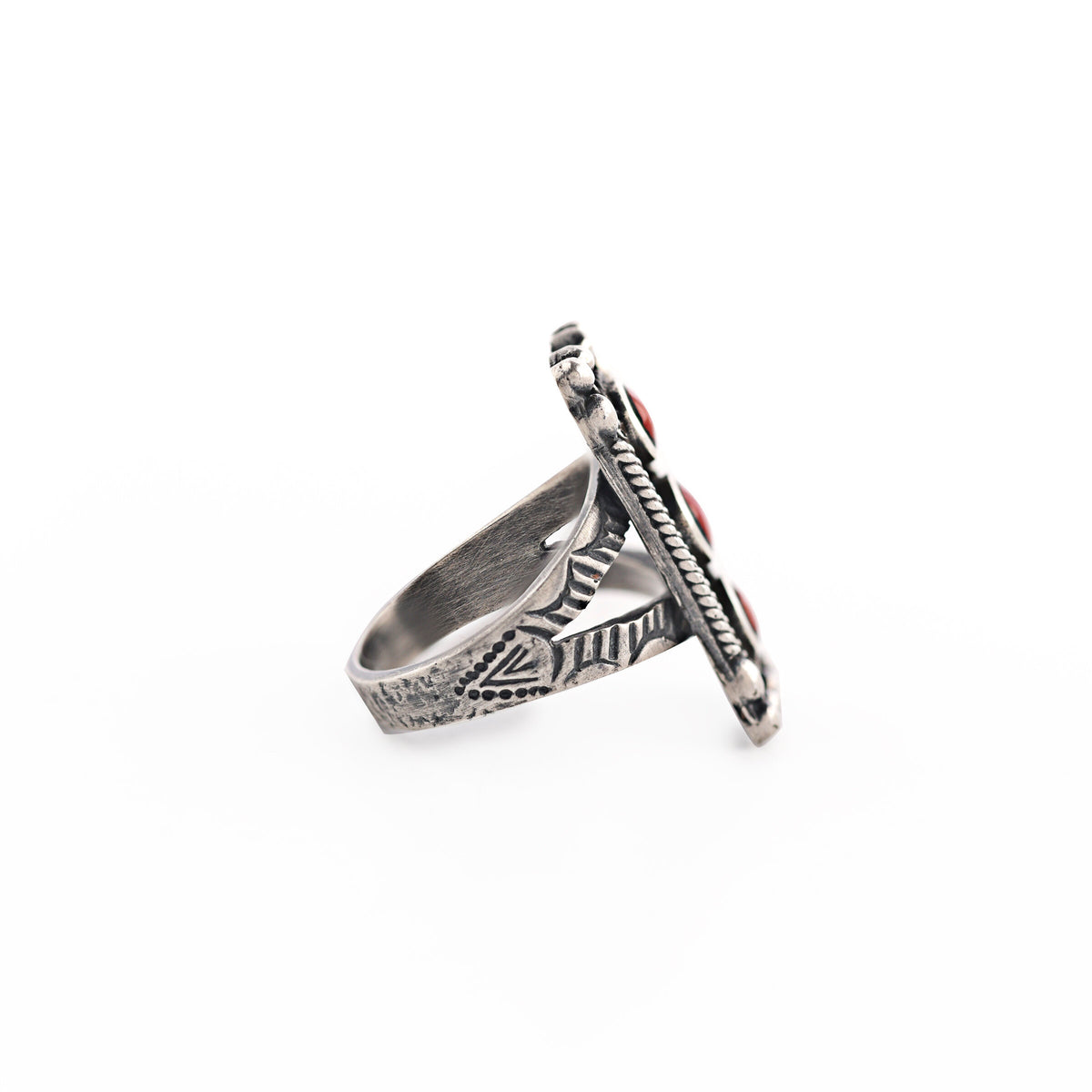 A rectangular sterling silver ring with red coral stones, featuring a textured design around the split shank band.