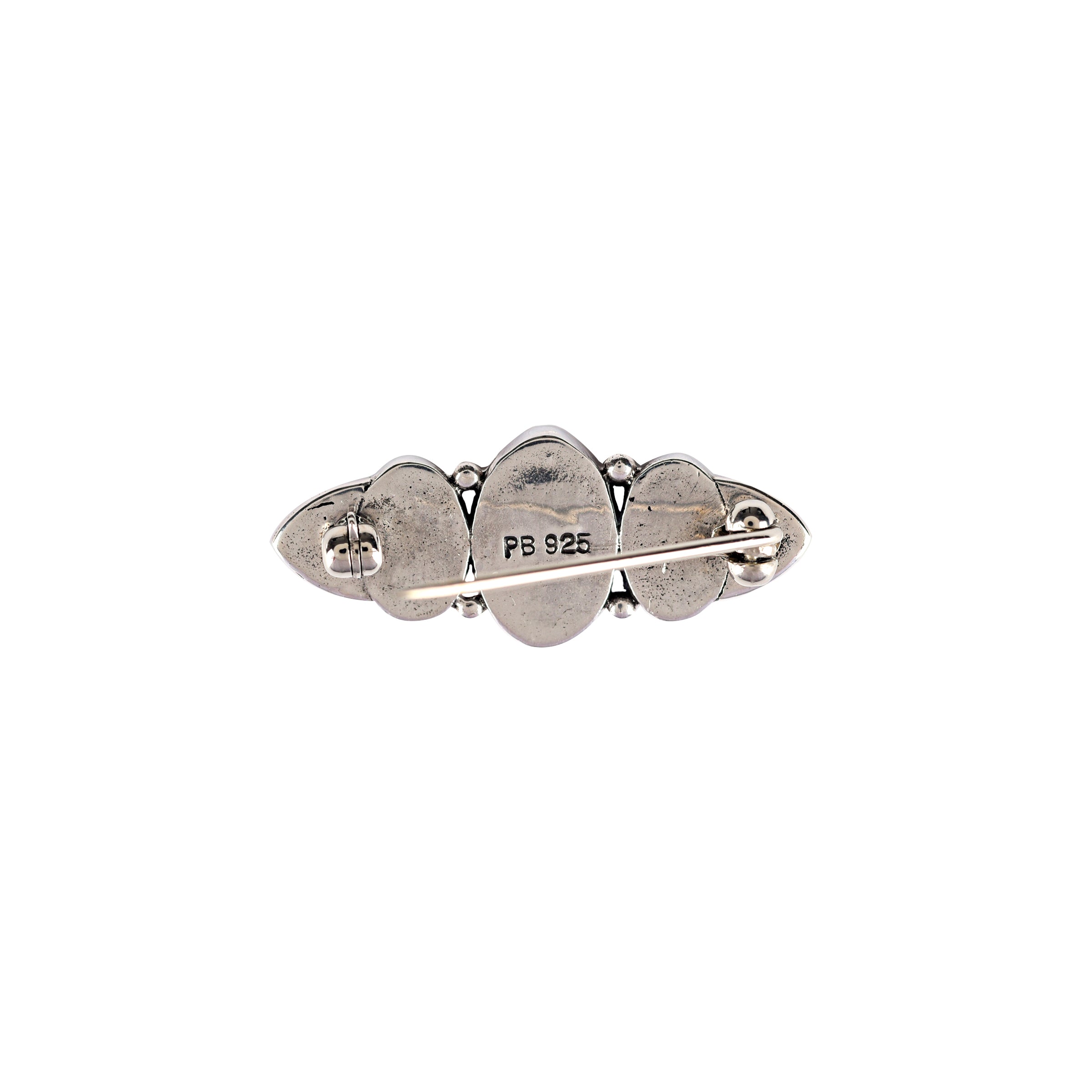 A sterling silver pin with blue turquoise inlay stones with a symmetrical design.