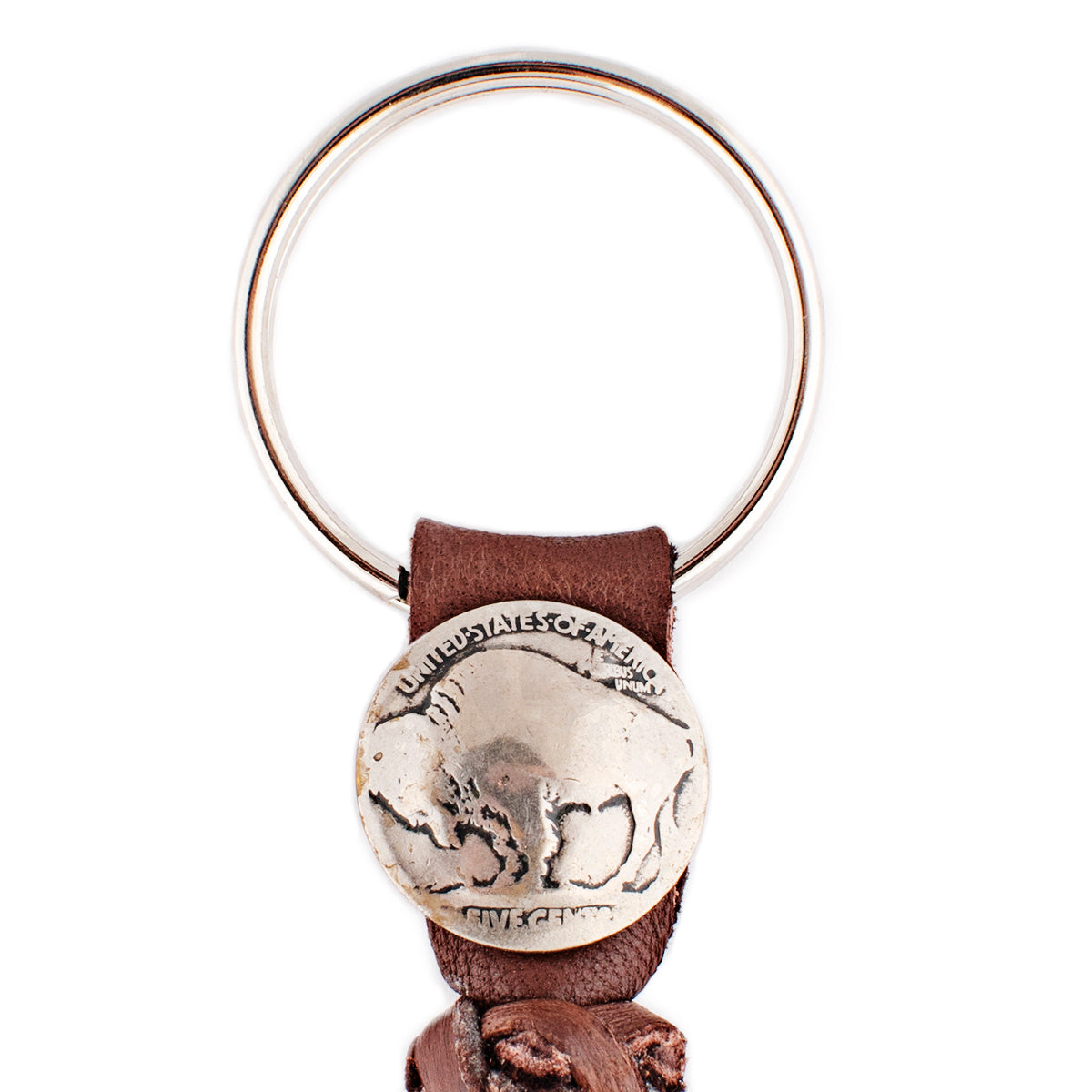 A chocolate leather tassel keychain with a silver metal key ring and a vintage buffalo nickel.