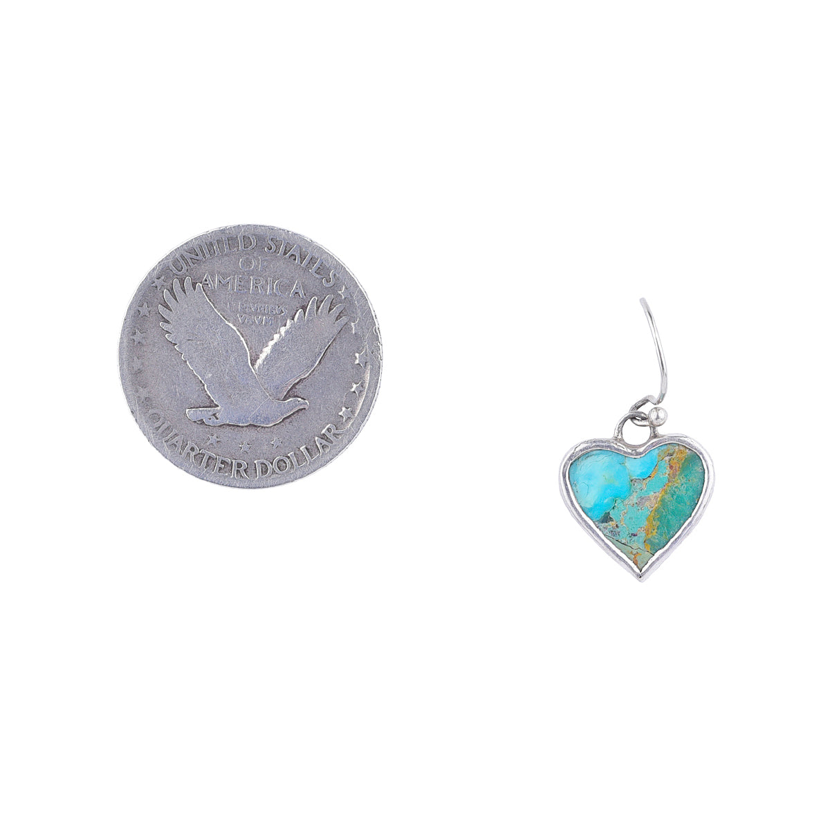 Turquoise stone wrapped in sterling silver in heart shape earring next to coin for scale.
