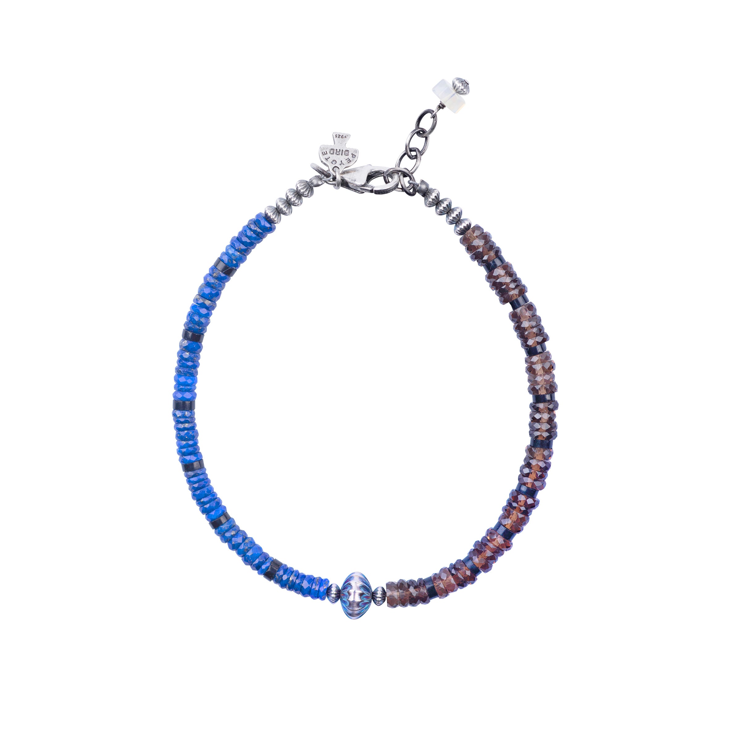 A Peyote Bird Original bracelet strung with Lapis and Jet on one side and Smokey Quartz and Jet on the other side with a large corrugated Desert Pearl as the centerpiece. Finished with a Sterling Silver lobster clasp with an Ethiopian charm for a secure and stylish fit.