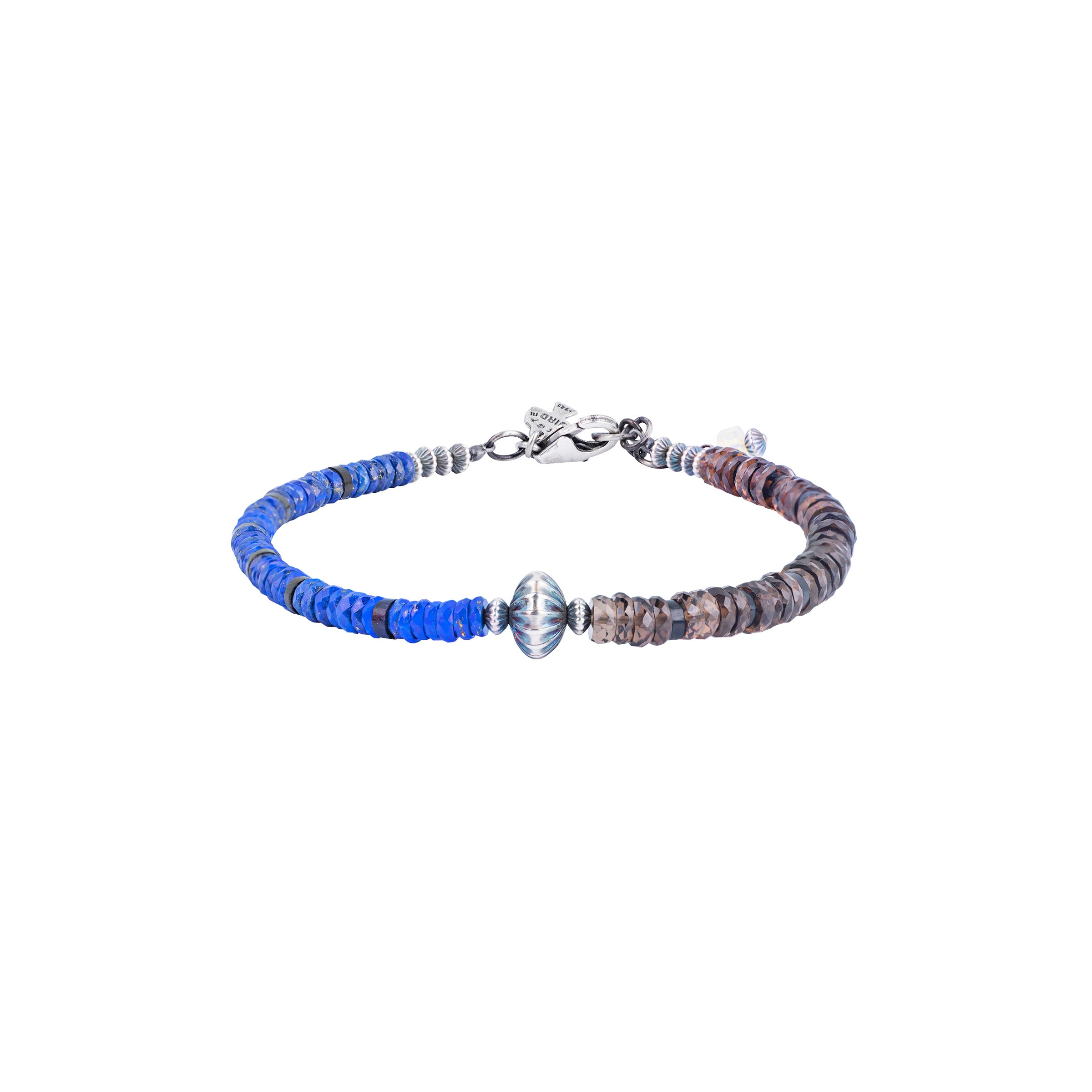 A Peyote Bird Original bracelet strung with Lapis and Jet on one side and Smokey Quartz and Jet on the other side with a large corrugated Desert Pearl as the centerpiece. Finished with a Sterling Silver lobster clasp with an Ethiopian charm for a secure and stylish fit.