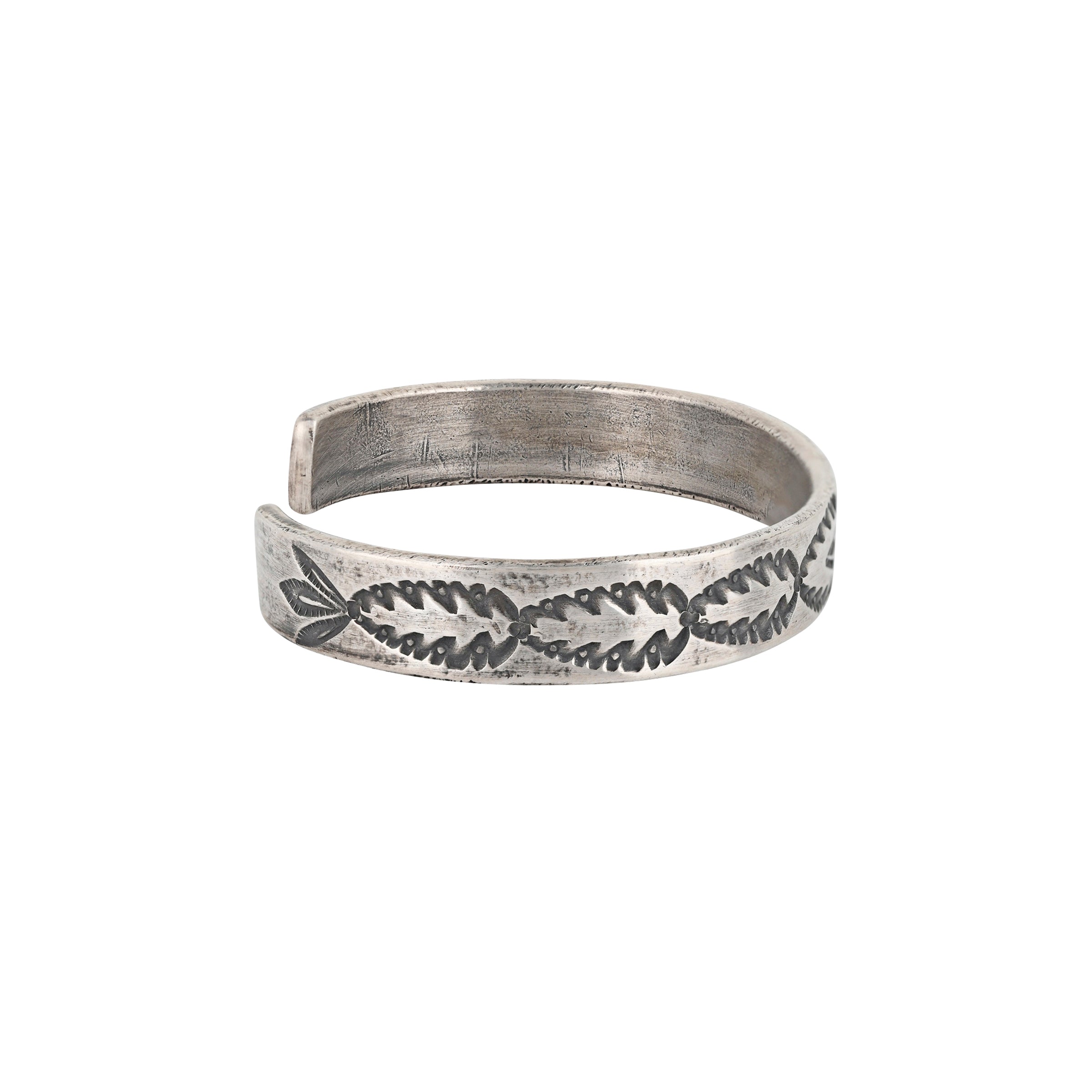 A handmade cuff using Ingot Silver Coin stamped with a Thunderbird as the centerpiece of the cuff surrounded by Southwestern and Santa Fe Style motifs, resembling arrowheads