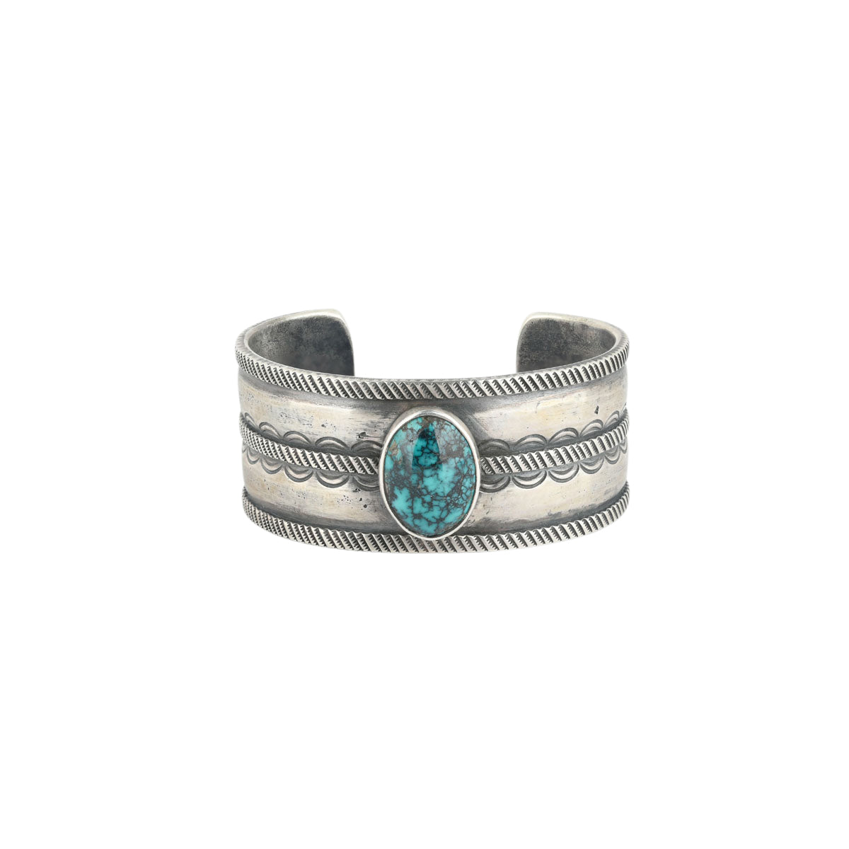 A men's cuff handcrafted with ingot coin silver and features a blue turquoise as the centerpiece. Stamped with Santa Fe style design.