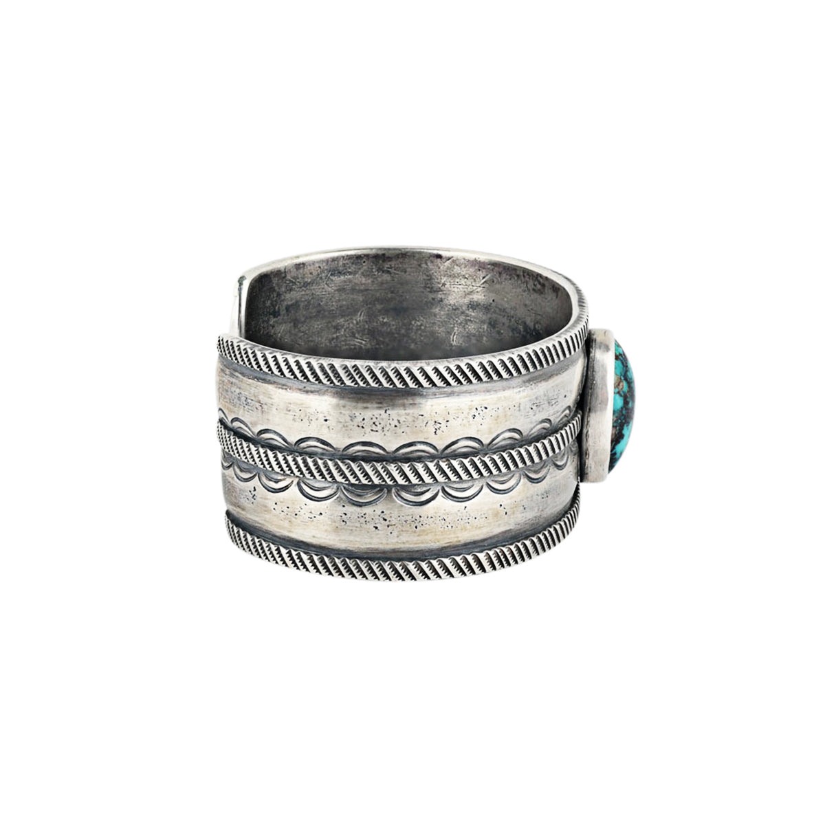 A men's cuff handcrafted with ingot coin silver and features a blue turquoise as the centerpiece. Stamped with Santa Fe style design.