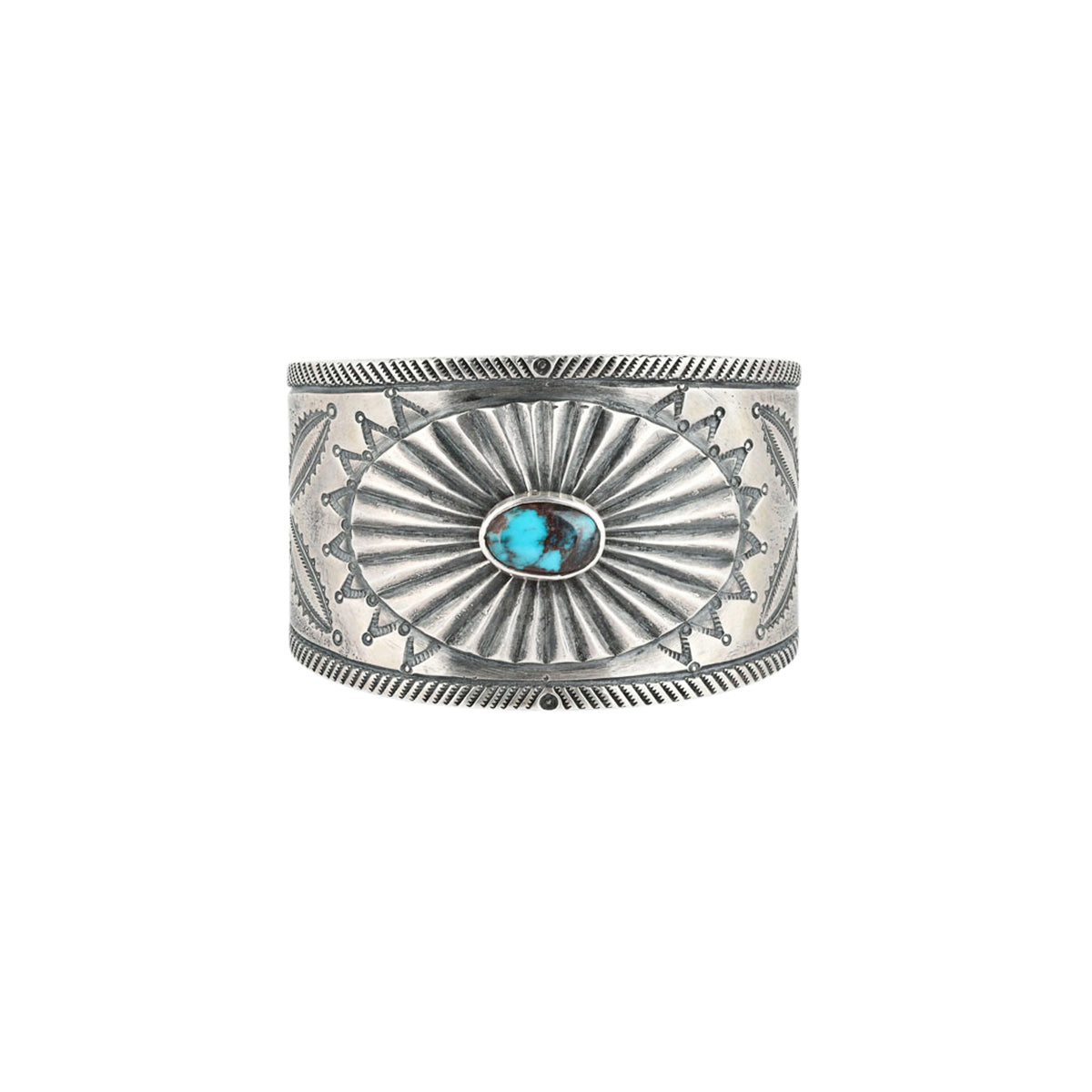 A handcrafted cuff made with ingot coin silver and features a small blue turquoise stone as the centerpiece surrounded by southwestern style motifs