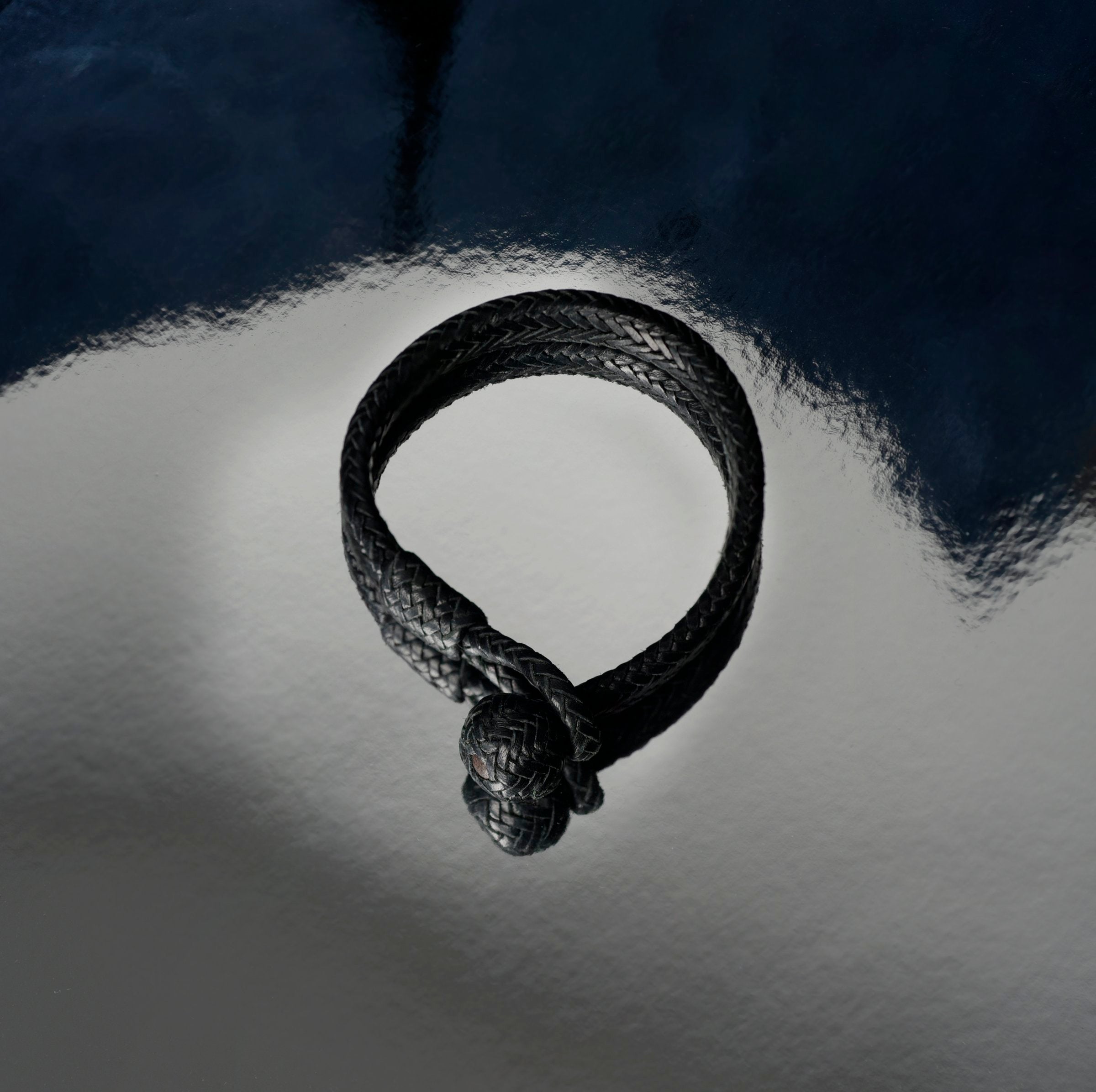 A large braided black leather bracelet and a looped fastener at the end.