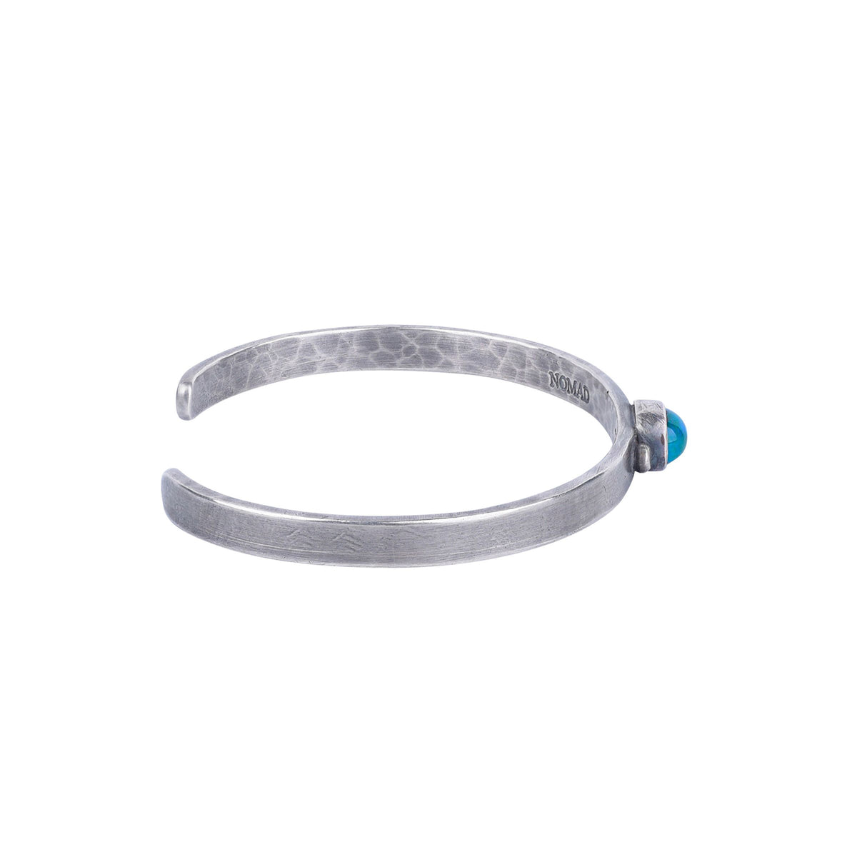A sterling silver cuff bracelet with a dark blue and green opal stone in the center and a hammered texture.