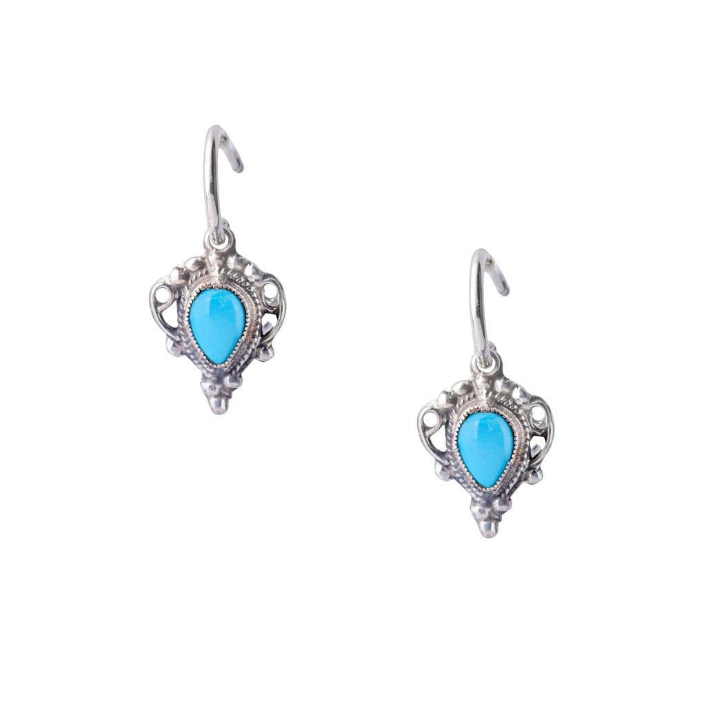 A pair of sterling silver earrings with blue turquoise stones, designed in an intricate geometric pattern, suspending from small silver rings.