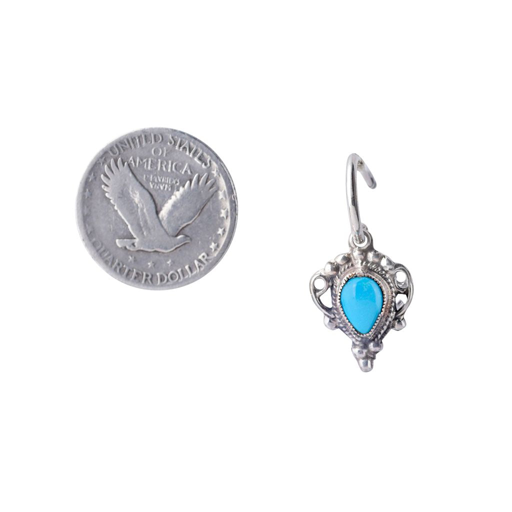 A pair of sterling silver earrings with blue turquoise stones, designed in an intricate geometric pattern, suspending from small silver rings.
