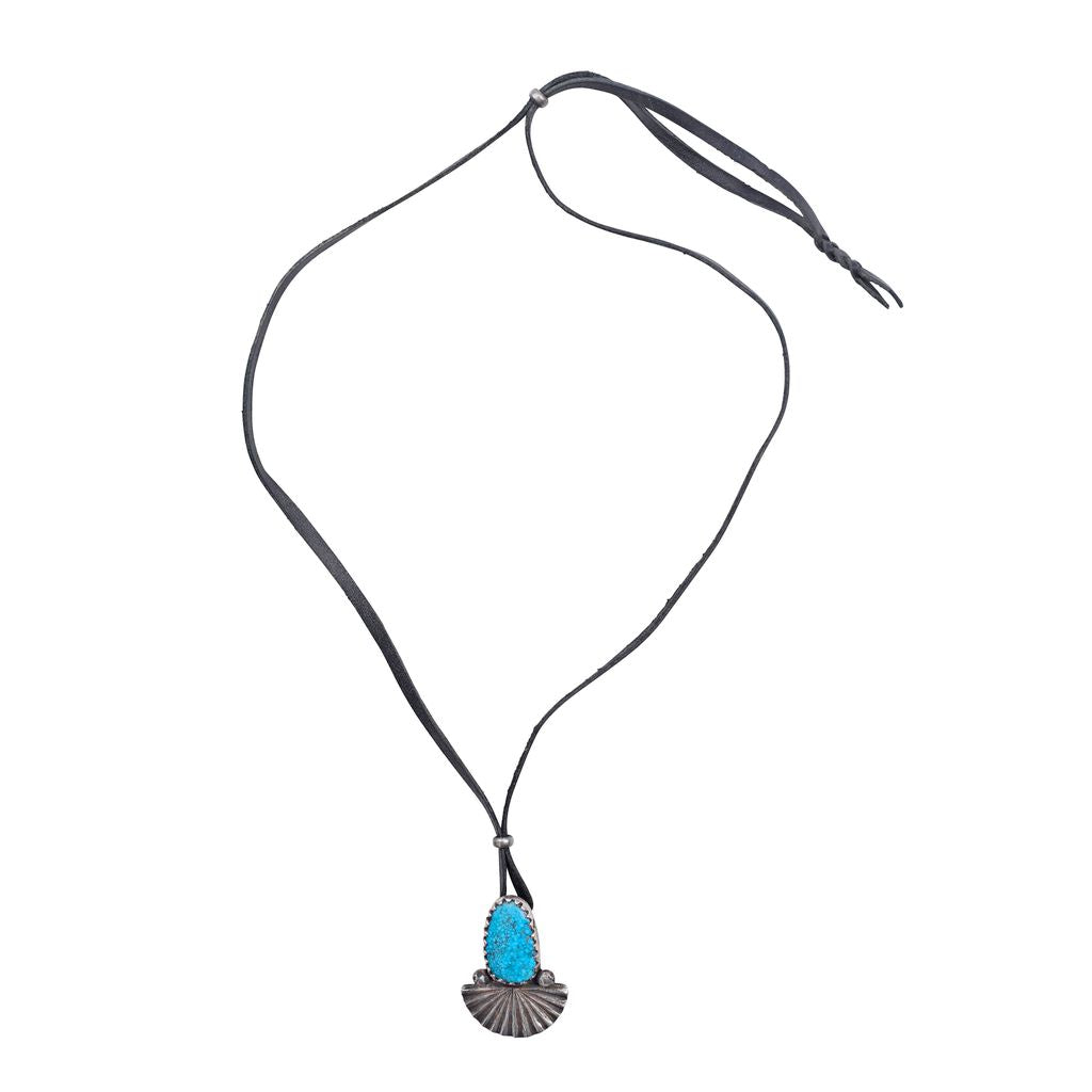 An ingot coin silver pendant necklace featuring a blue turquoise stone on black leather.