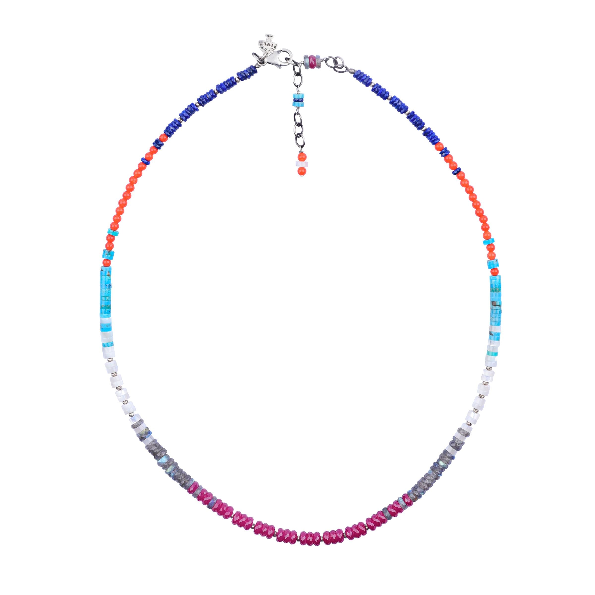 A multicolored beaded necklace with blue turquoise, orange coral, lapis, labradorite, mother of pearl, and ruby beads, with a sterling silver chain.