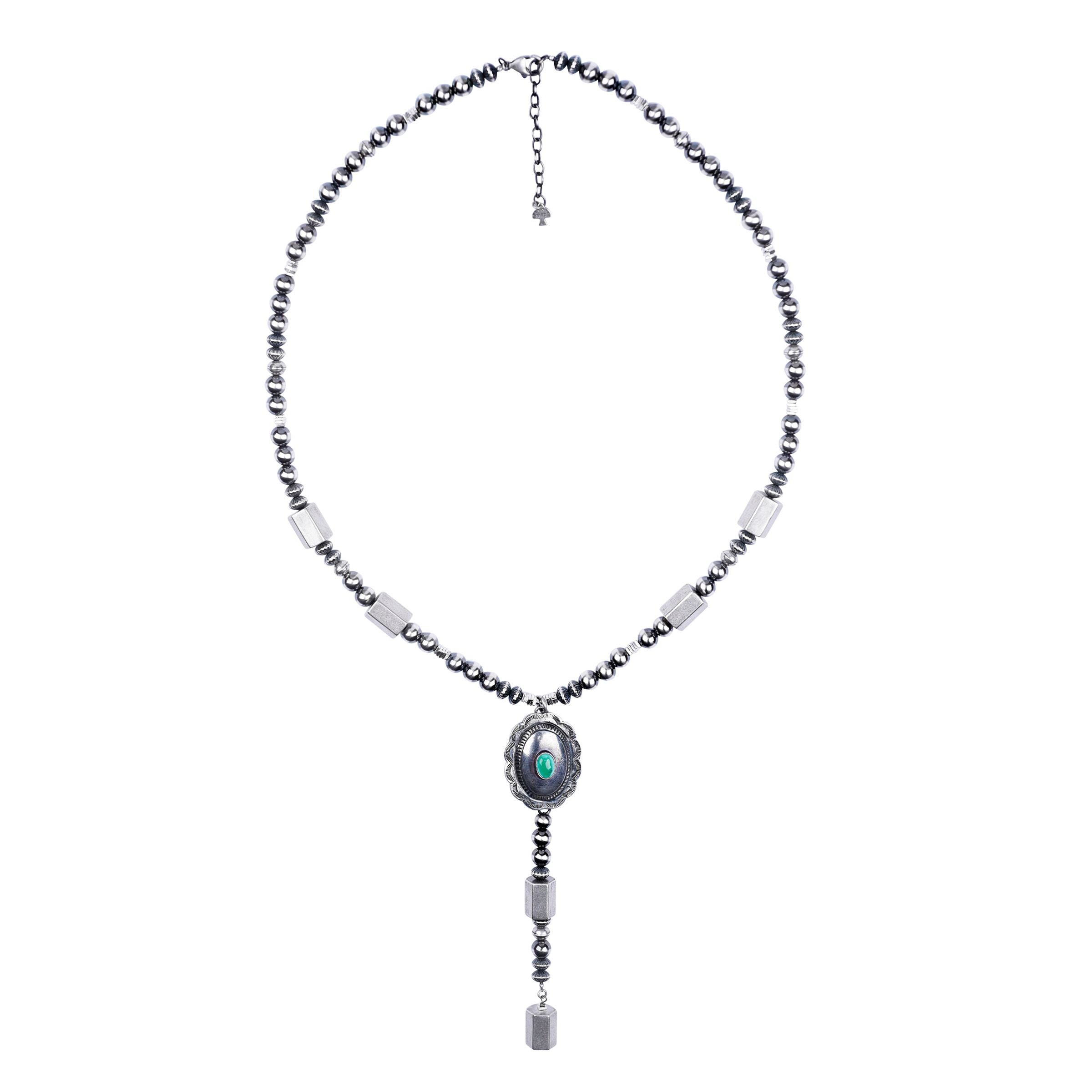 A sterling silver necklace with contemporary and vintage beads and a vintage concho pendant with a green turquoise stone.