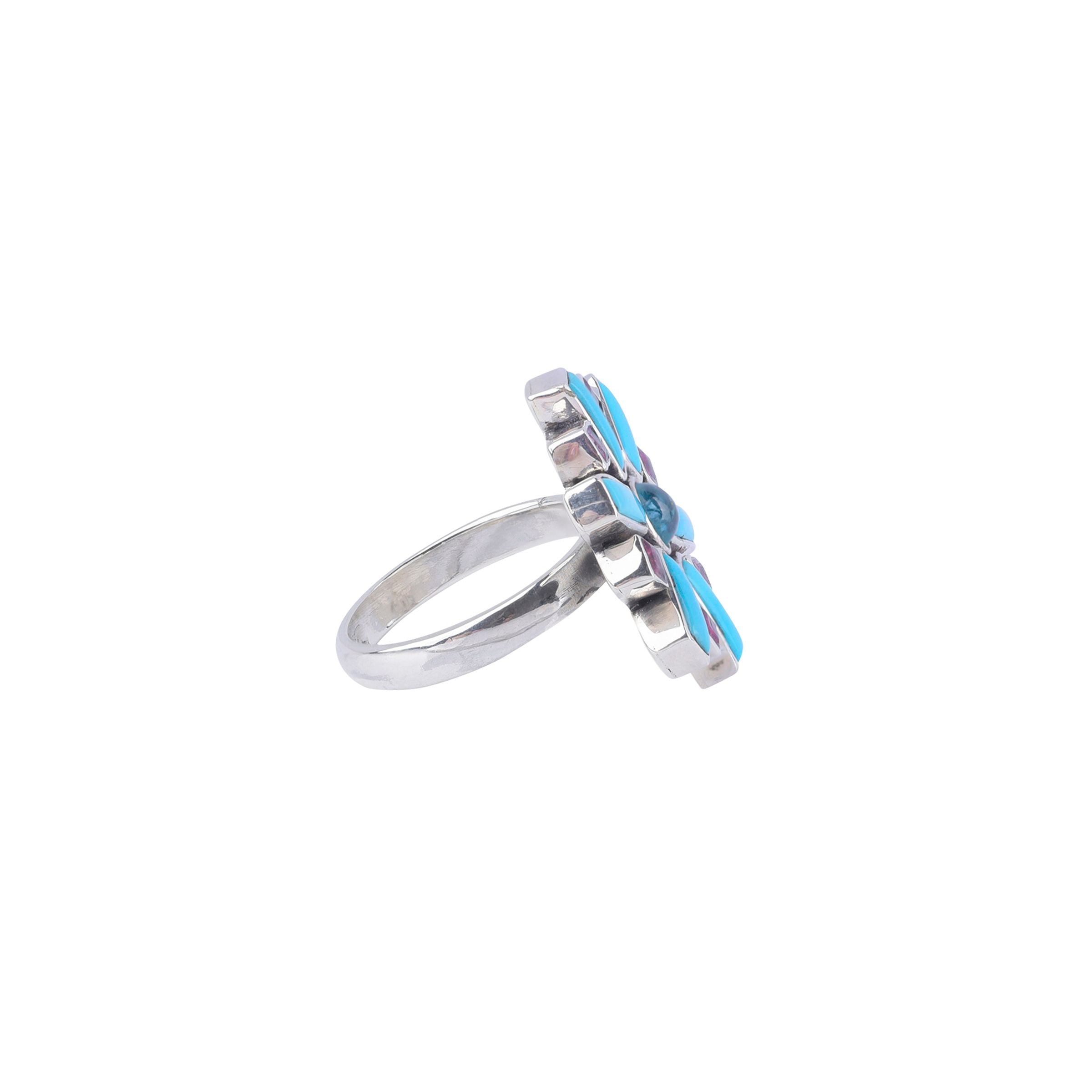 A sterling silver ring with a thin silver band and blue turquoise, aquamarine, and pink tourmaline stones.