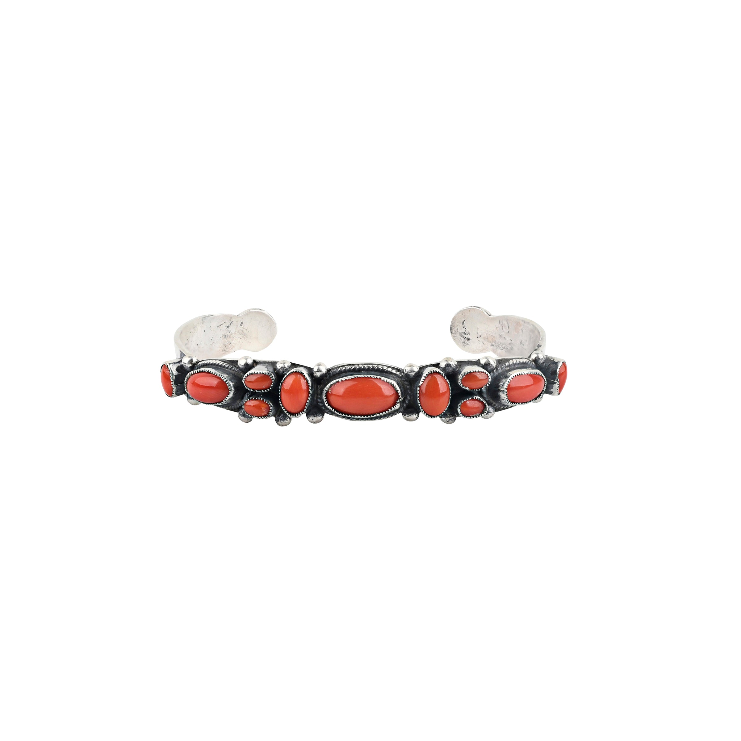 A handmade sterling silver southwestern style cuff inlayed with Red Coral featuring western style stamping