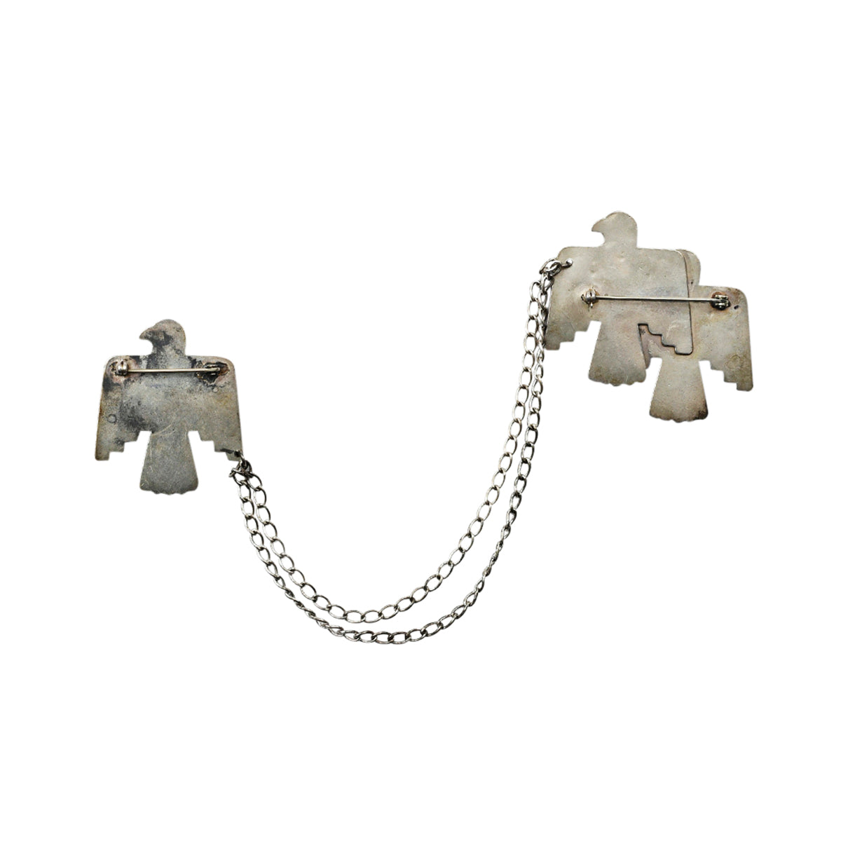 Two sterling silver thunderbird pins stamped with southwestern designs connected by chain