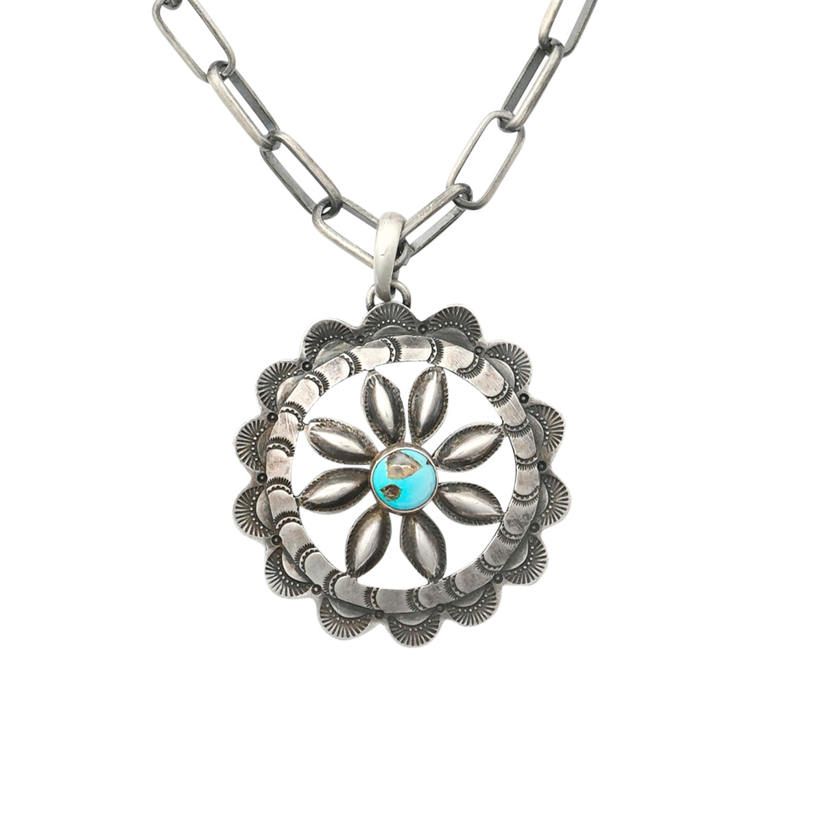 A sterling silver, vintage inspired, floral pendant featuring Santa Fe style stamping and a blue turquoise as the centerpiece strung on sterling silver chain.