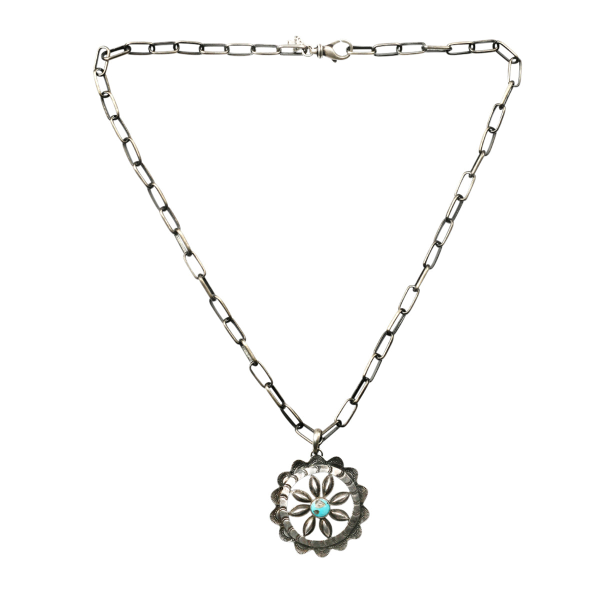 A sterling silver, vintage inspired, floral pendant featuring Santa Fe style stamping and a blue turquoise as the centerpiece strung on sterling silver chain.