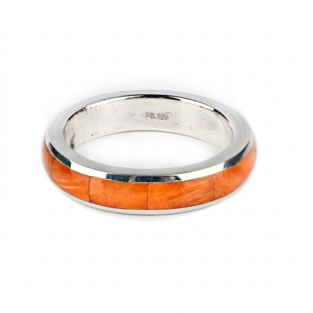 A sterling silver ring with a orange spiny oyster shell inlay.