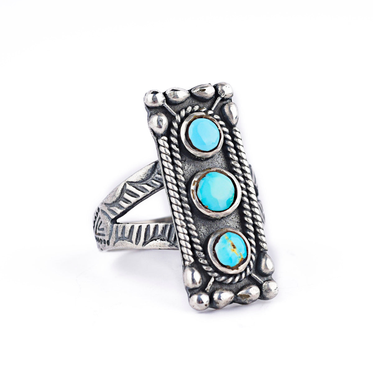 A rectangular sterling silver ring with blue turquoise stones, featuring a textured design around the split shank band.