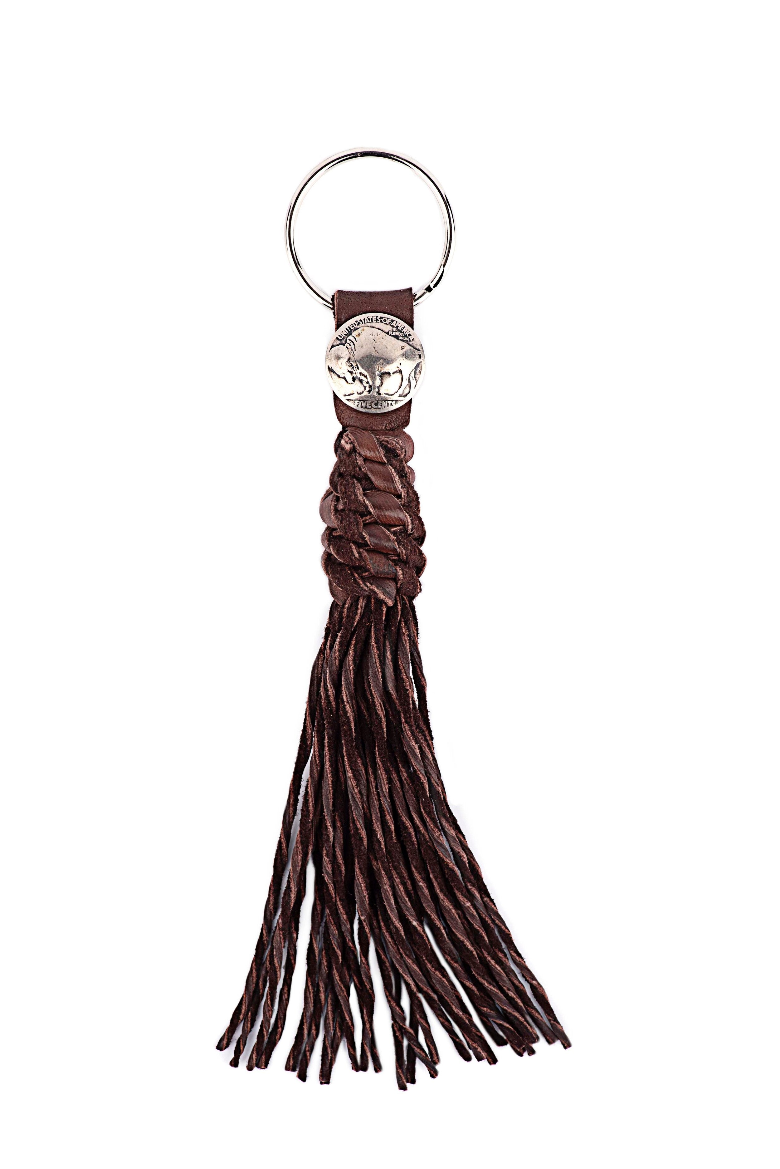 A chocolate leather tassel keychain with a silver metal key ring and a vintage buffalo nickel.