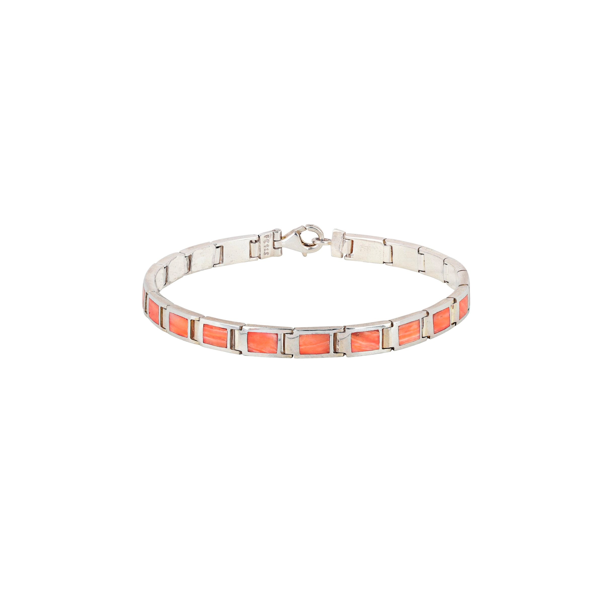 A silver bracelet with red and orange stone accents, featuring a clasp.