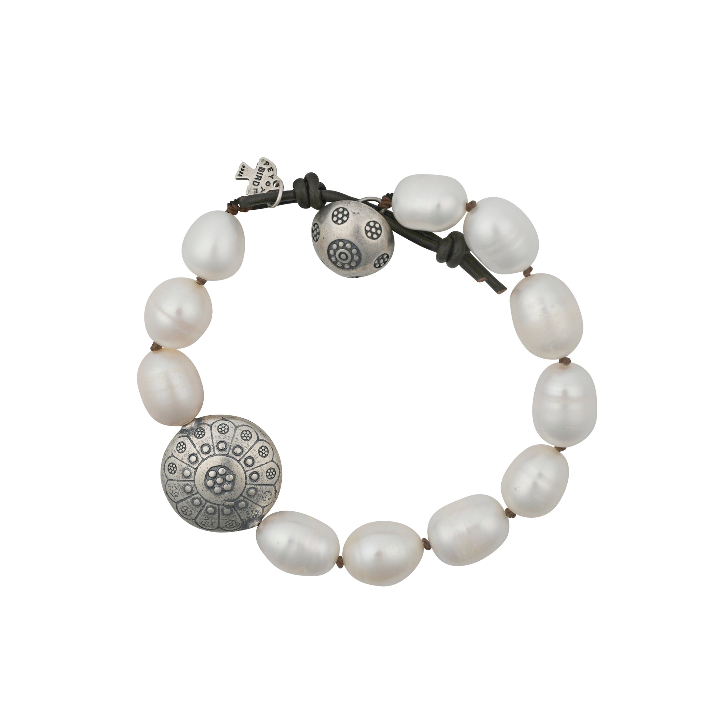 A Peyote Bird Original Bracelet featuring a stand of large Freshwater Pearls, stamped Sterling Silver buttons with mandala-like designs, on leather cord.