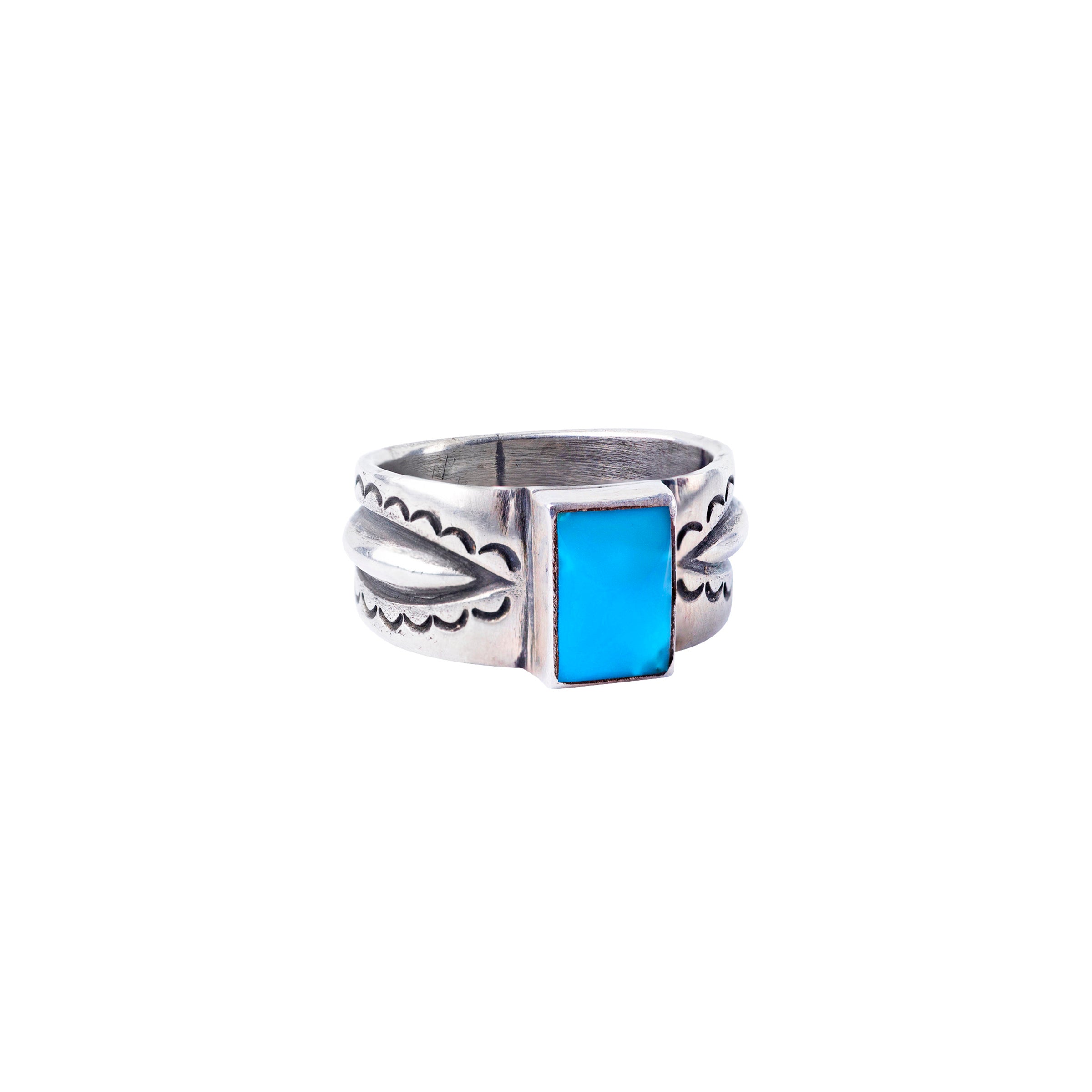 An ingot coin silver ring with a rectangular sleeping beauty turquoise stone inset and intricate designs around the band.
