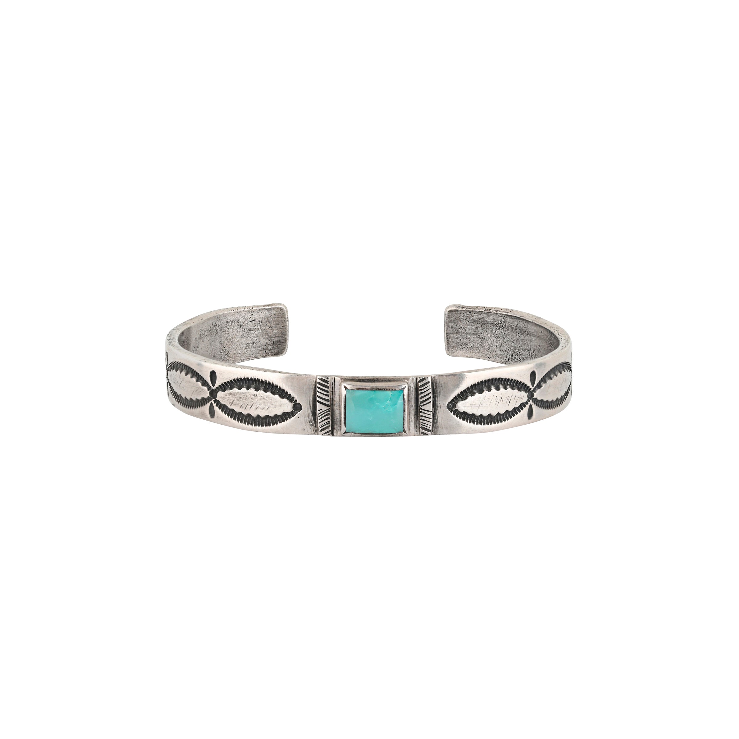 A handmade cuff by Joey Falcon using Ingot Coin Silver and stamped with Santa Fe Style motifs. Features a Blue Turquoise gem in the middle of the band.