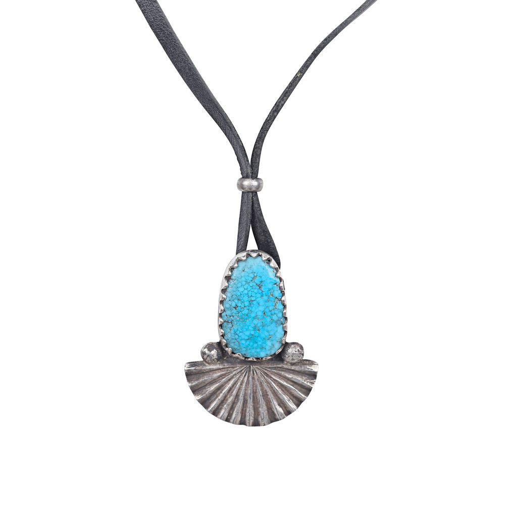 An ingot coin silver pendant necklace featuring a blue turquoise stone on black leather.