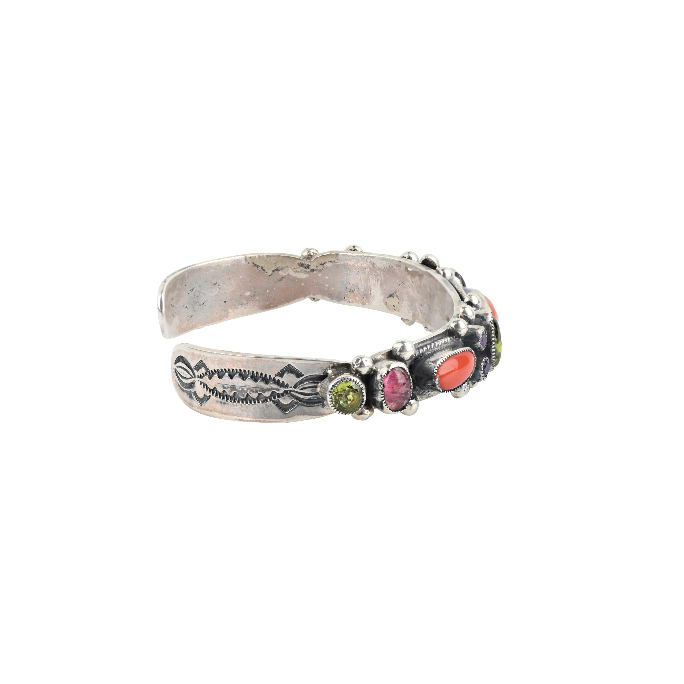 A handmade Sterling Silver Southwestern Cuff inlayed with genuine gemstones such as Red Coral, Amethyst and Peridot with unique Western style stamping.