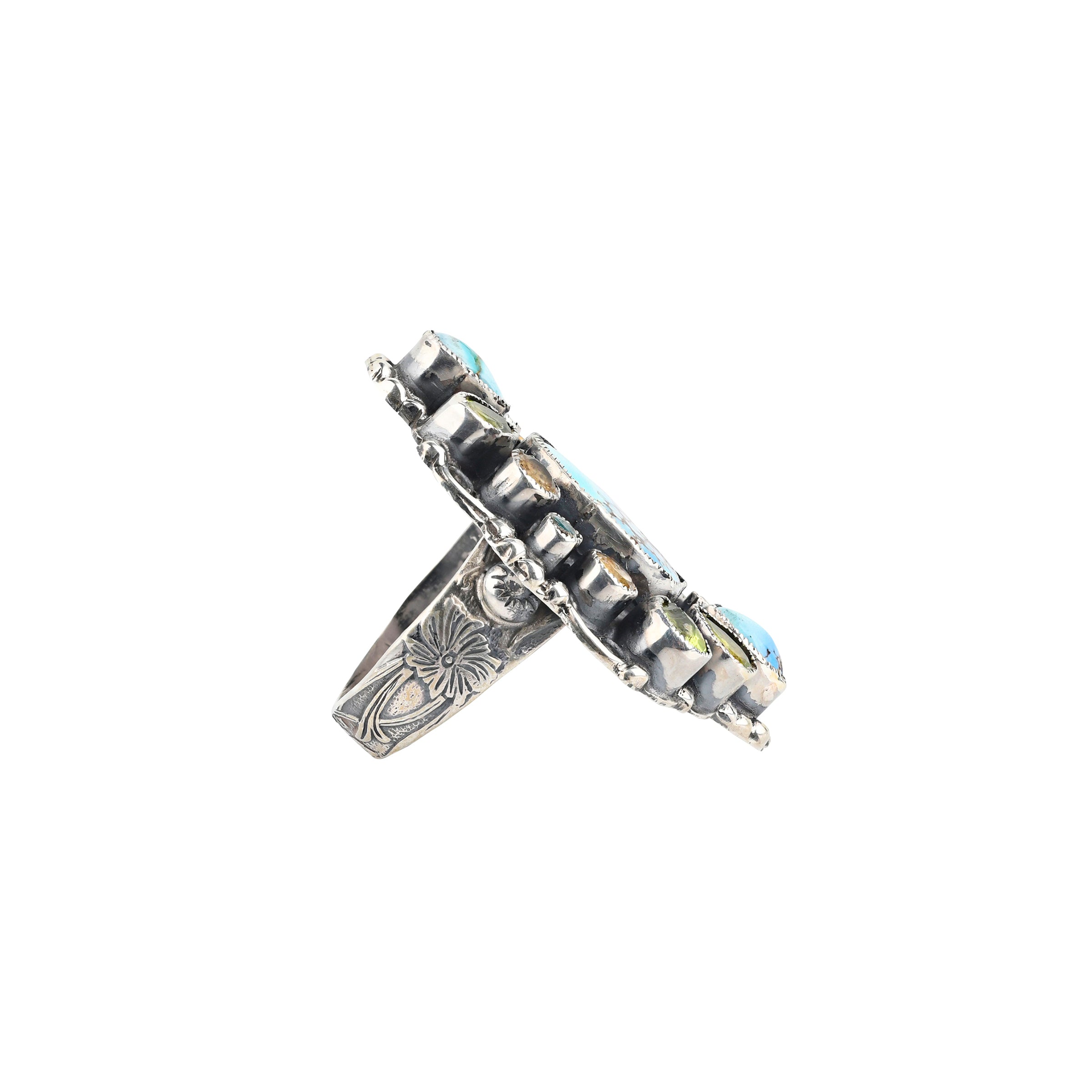 A handcrafted Sterling Silver shield ring featuring a stunning piece of Blue Turquoise surrounded by Blue Turquoise and Peridot teardrops and round Citrine. The band features floral detailing finished with Western style stamping.