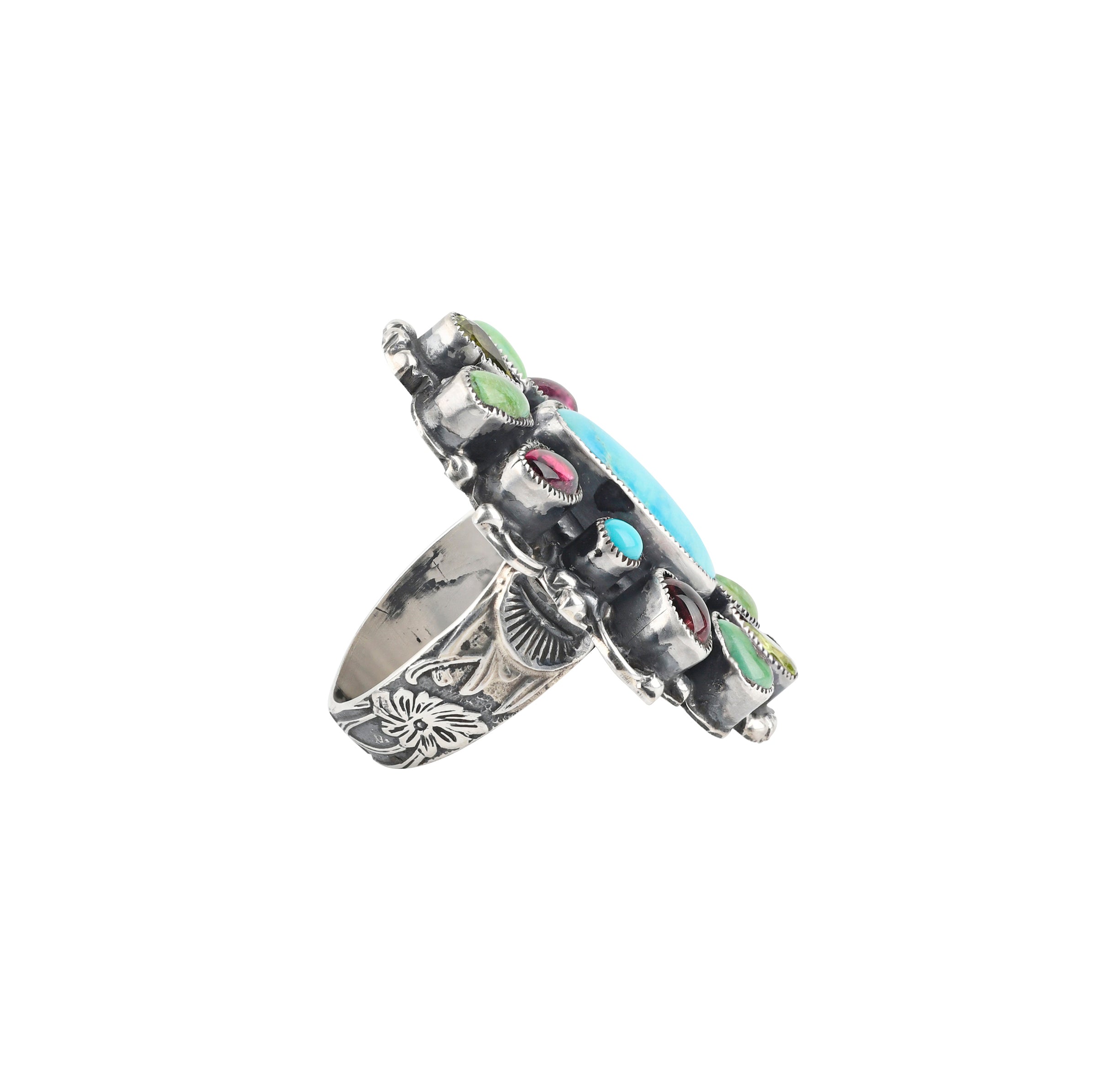 A beautiful statement ring featuring a large Blue Turquoise piece surrounded by Pink Tourmaline, Peridot, and Green Turquoise. The band is embellished with floral detailing finished with Western style stamping.