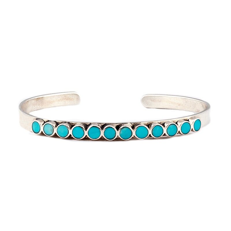 The vintage inspired Mirai cuff from our Bird and Arrow line that features sterling silver with circular blue turquoise stones on top of the band.  