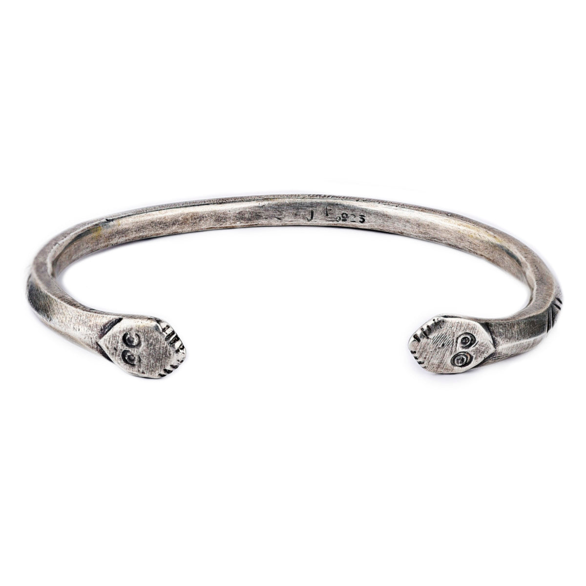 A sterling silver cuff bracelet from artisan Jock Favour featuring a snake motif with opposing snake heads at the ends and intricate stamping resembling snake scales. Made in USA.