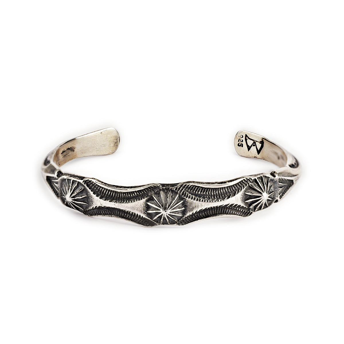 A sterling silver cuff bracelet from artisan Buffalo with intricate stamped geometric patterns and a branded clasp. Made in USA.