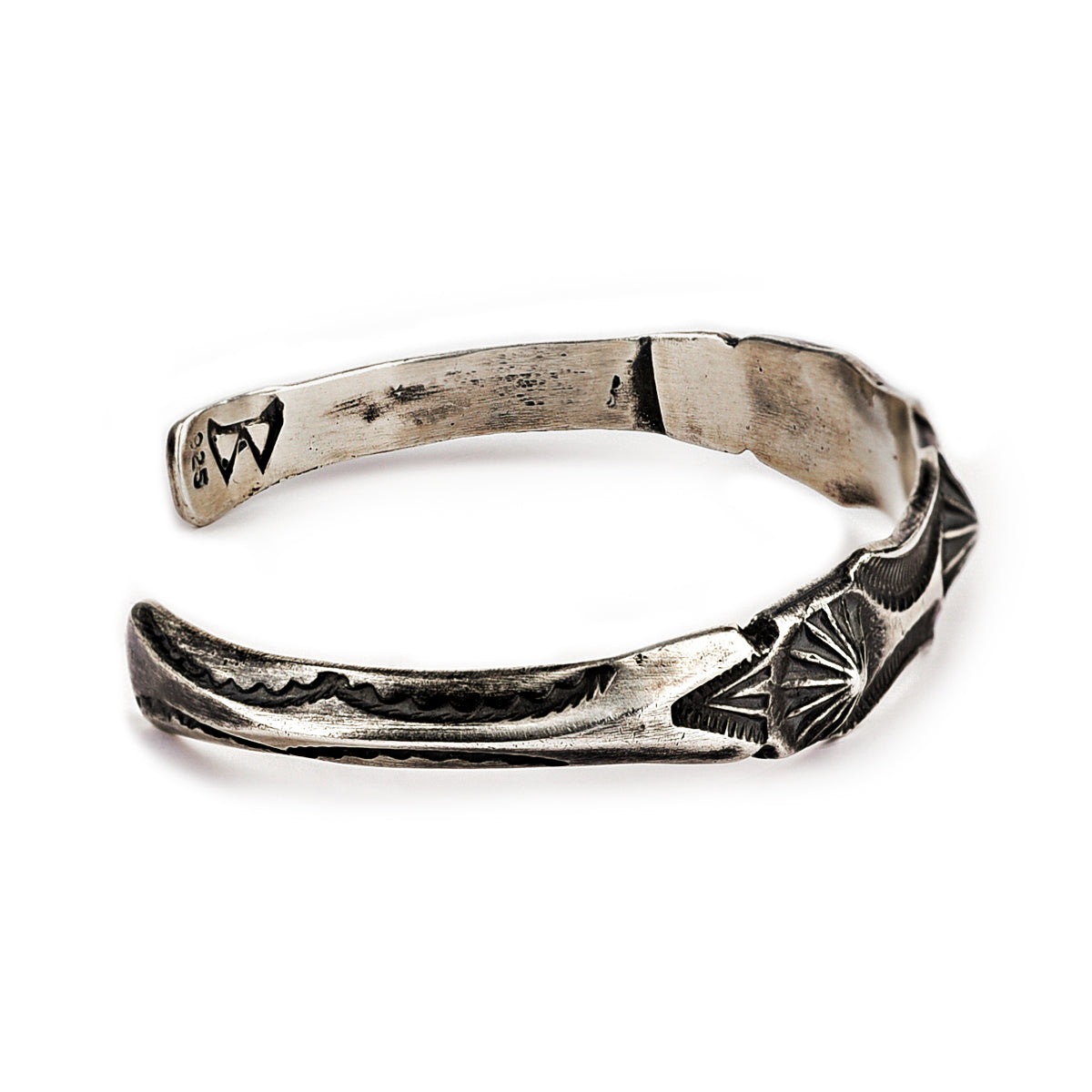 A sterling silver cuff bracelet from artisan Buffalo with intricate stamped geometric patterns and a branded clasp. Made in USA.