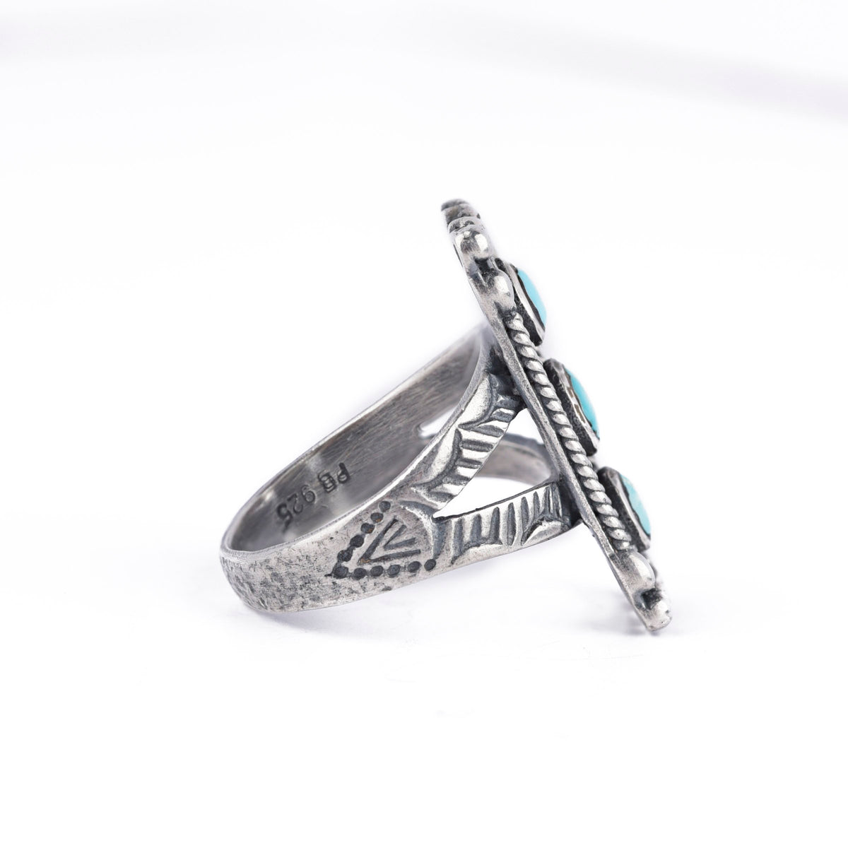 A rectangular sterling silver ring with blue turquoise stones, featuring a textured design around the split shank band.