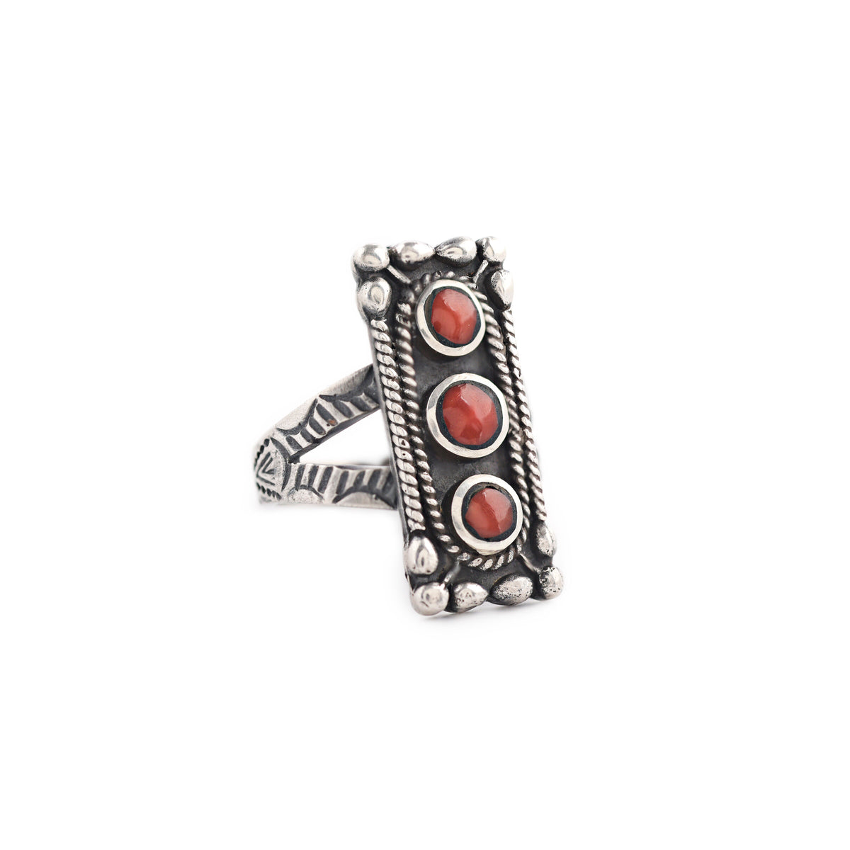 A sterling silver ring with three red coral stones set in the band, with decorative metalwork around the top and on the split shank band.